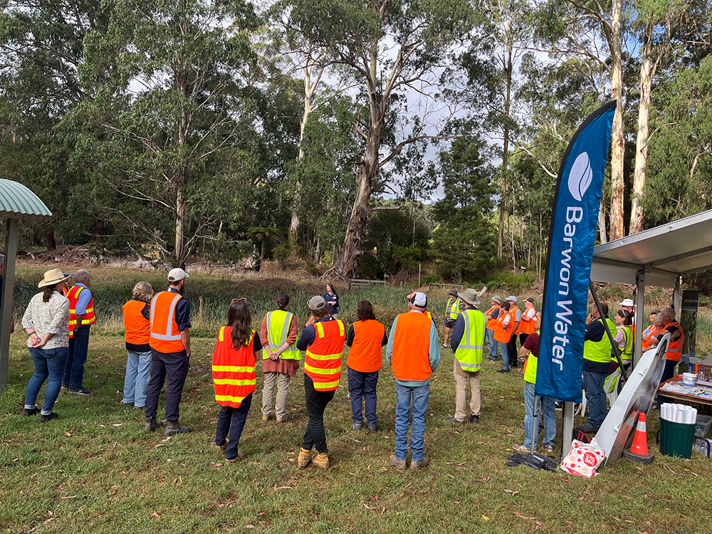 Group of people in high vis vest listening to speaker they are in a bush setting