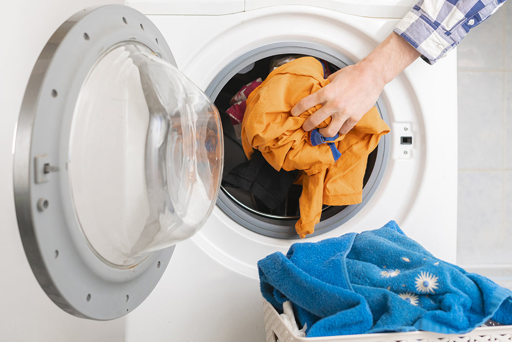 Image of hand loading washing into a washing machine